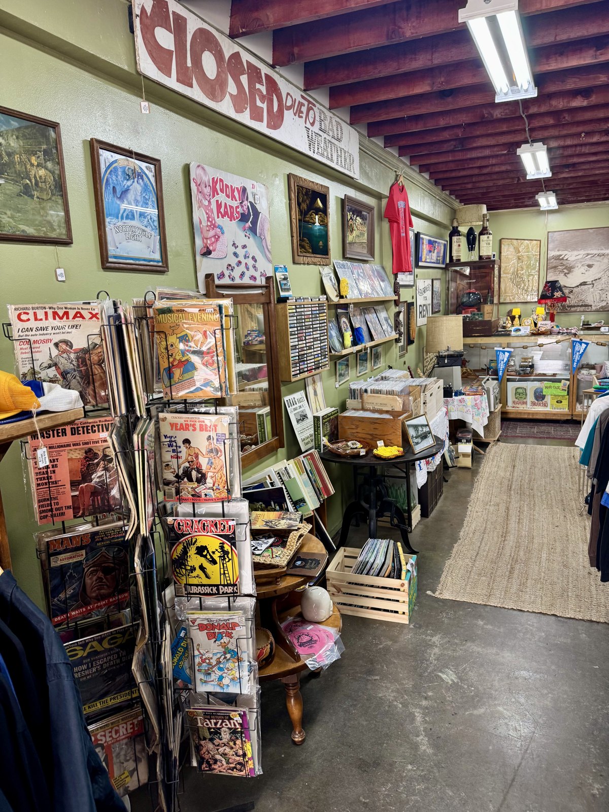 Interior aisle view with vintage magazines, art, and merchandise at Beachcomber Vintage.